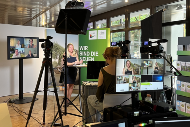 Rednerin bei der SQ-Infoveranstaltung, sie wird gefilmt und man sieht Filmequipment