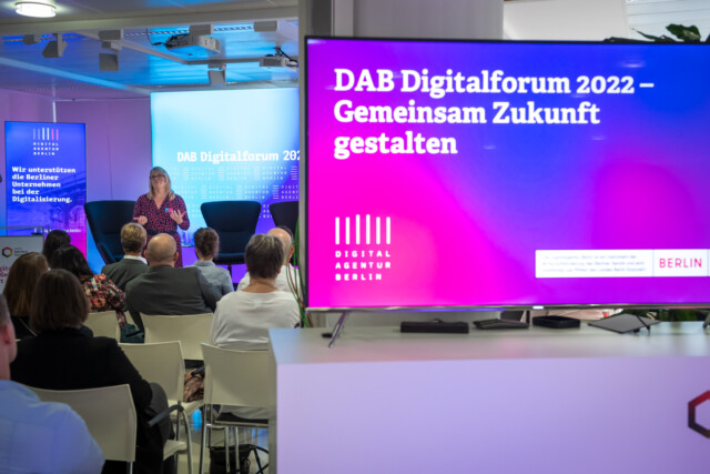 Speakerin auf der DAB, im Vordergrund ist ein Bildschirm